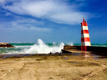 Lighthouse on beach against sky