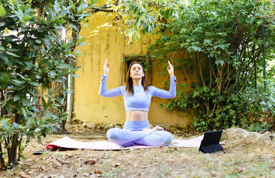 Full length of woman sitting against wall