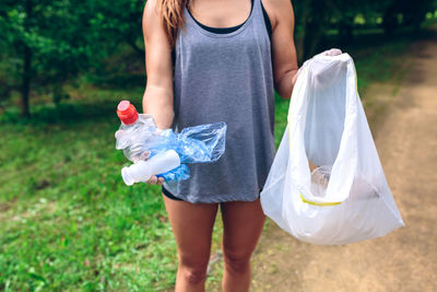 Midsection of woman holding umbrella standing in field