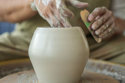 Midsection of woman making pottery in workshop