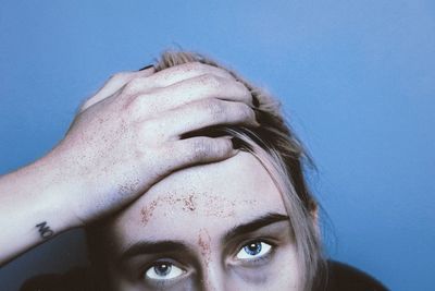 Close-up portrait of woman against blue background