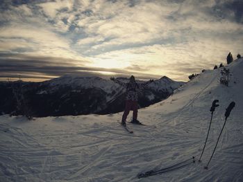 Man standing on snow covered mountain against sky during sunset