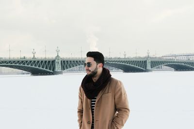 Portrait of young man in city against sky