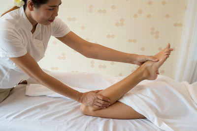 Masseur massaging leg of woman on table in spa
