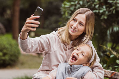 Smiling mother doing selfie with daughter outdoors
