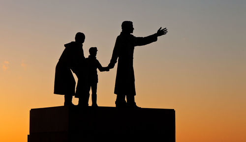 Silhouette statues against clear sky during sunset