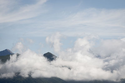 Low angle view of volcanic mountain against cloudy sky
