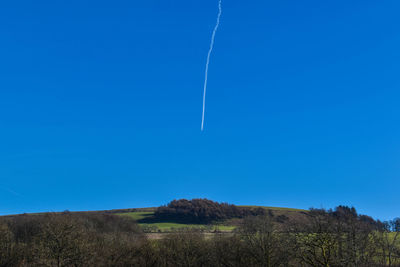 Low angle view of vapor trail against clear blue sky