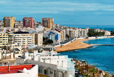 High angle view of cityscape by sea against sky