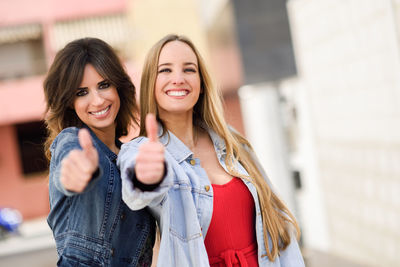 Portrait of smiling female friends showing thumbs up sign