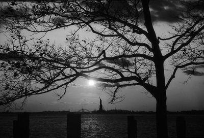 Silhouette bare tree by sea against sky