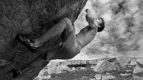 Low angle view of man climbing on rock