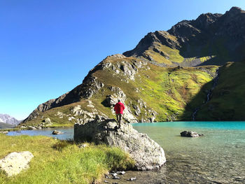 Scenic view of sea by mountain against sky