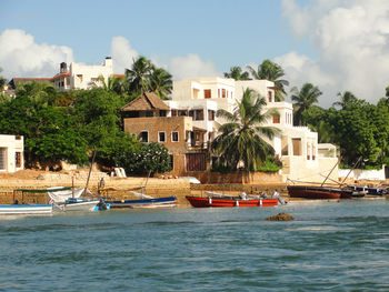 Dhows and boats moored at shore against buildings