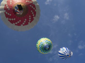 Low angle view of colorful hot air balloons flying against blue sky