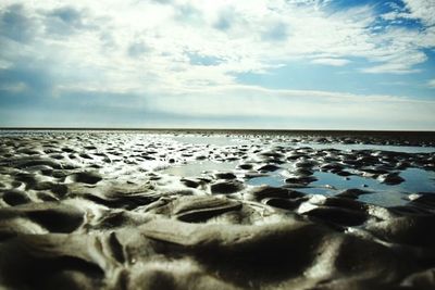 Scenic view of beach against cloudy sky