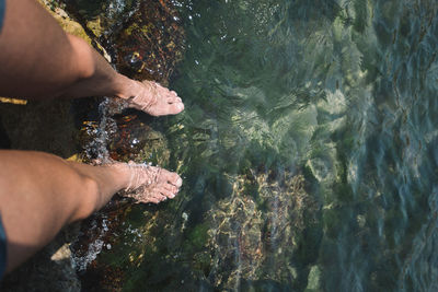 Low section of woman standing in shallow water at beach