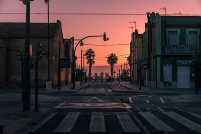 Road in city against sky at sunset