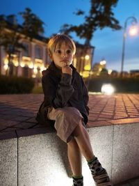 Thoughtful boy sitting on walkway at night