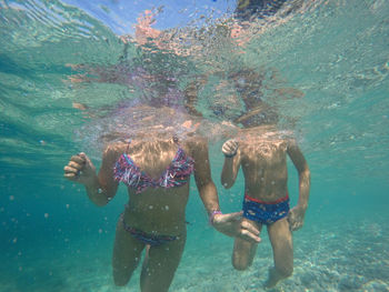 Low section of mother and son swimming in sea