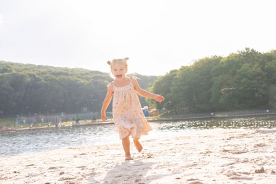 Full length of woman with arms outstretched standing at beach