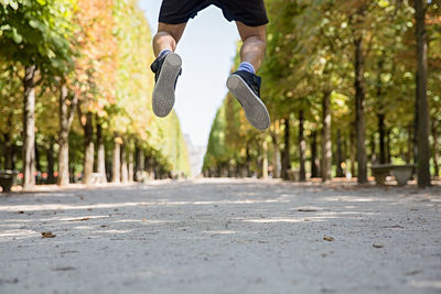 Low section of man jumping on footpath at park