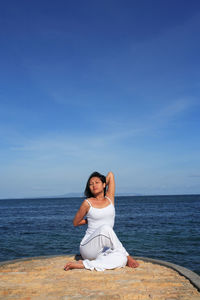 Woman doing yoga against sea and sky