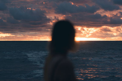 Silhouette man on beach against sky during sunset