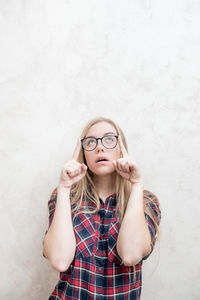 Portrait of young woman standing against white wall