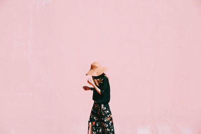 Woman walking against pink wall