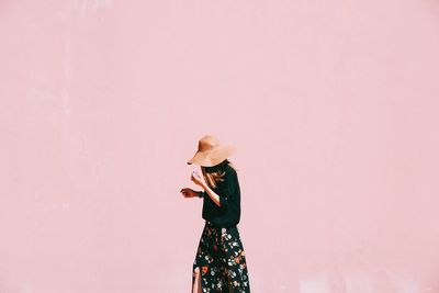 Full length of woman standing against pink wall