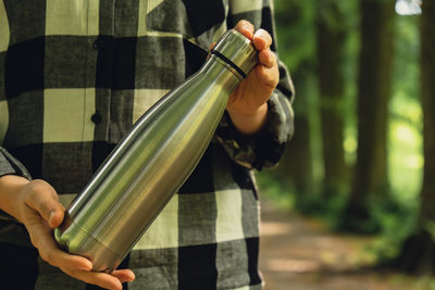 Close-up of unrecognizable female hand holding water bottle. reusable steel thermo water bottle in