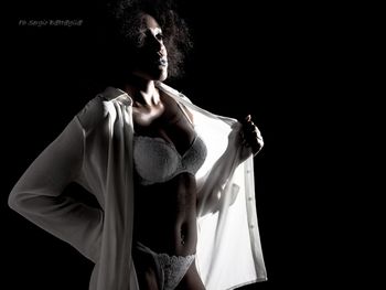 Midsection of woman standing against black background