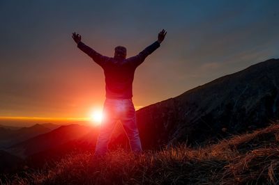 Full length of man standing on mountain against sky during sunset
