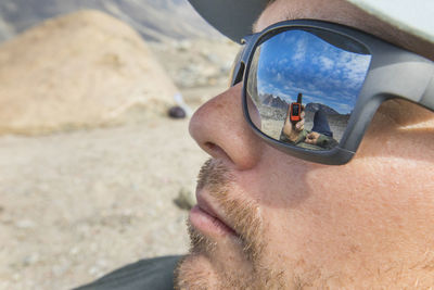 Reflection of gps and mountain view in backpackers sunglasses.