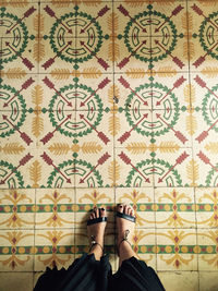 Low section of woman standing patterned tiled floor