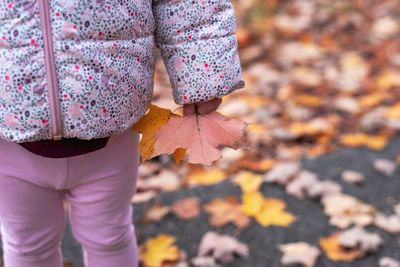 Low section of woman standing on autumn leaves