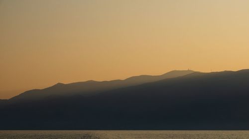 Scenic view of silhouette mountains against orange sky