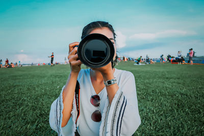 Portrait of woman holding camera on field