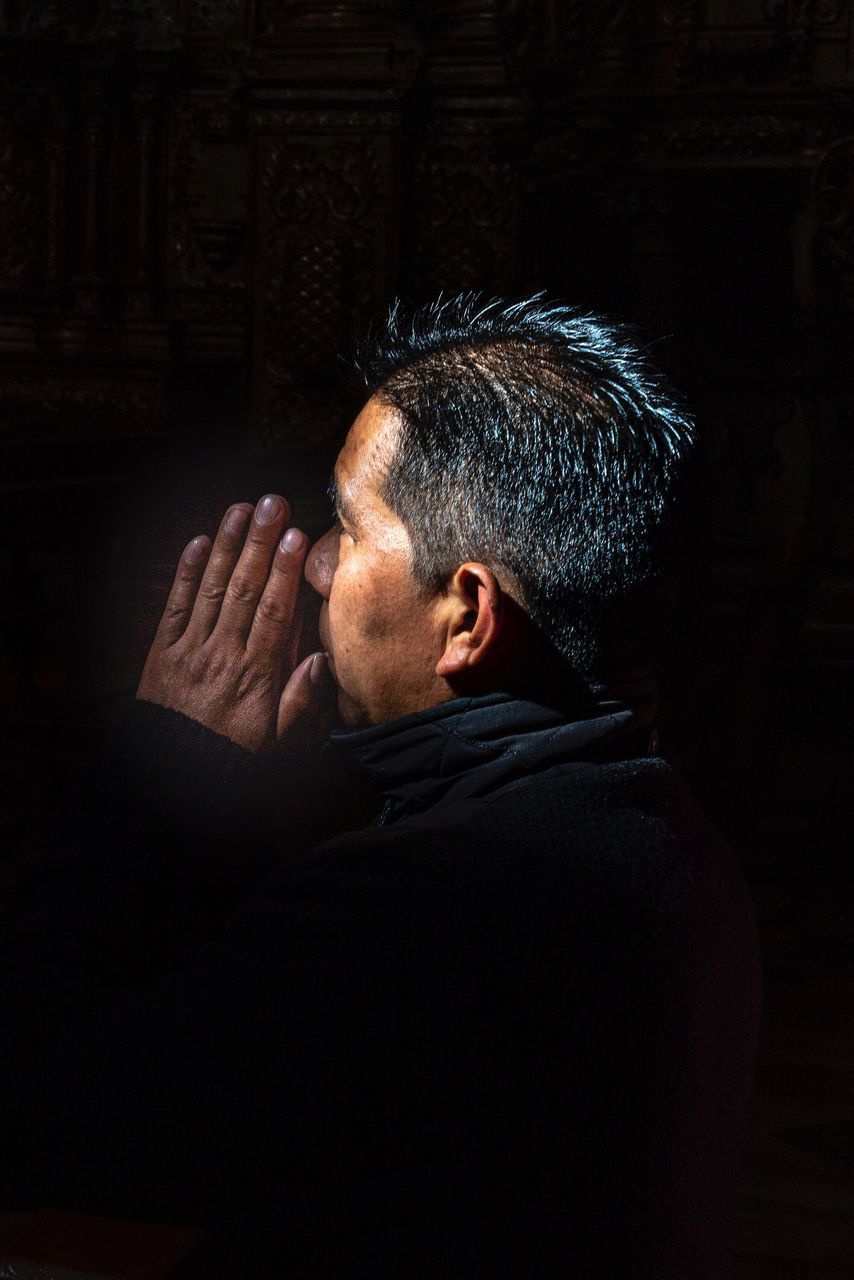 one person, headshot, portrait, men, mature adult, indoors, mature men, adult, hand, rear view, studio shot, real people, black background, religion, spirituality, despair, males, belief, emotion, depression - sadness, contemplation, hopelessness