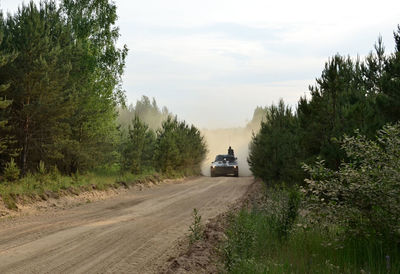 Road amidst trees and plants against sky