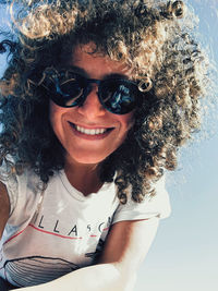 Low angle view of young woman wearing sunglasses against sky