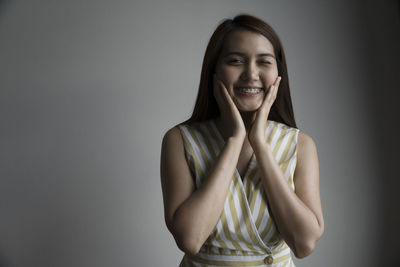 Portrait of a smiling young woman against gray background