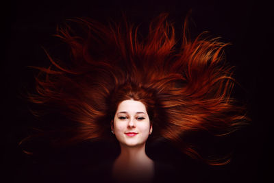 Portrait of a beautiful young woman against black background