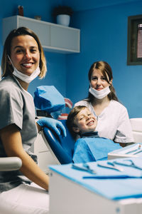 Portrait of smiling dentists and boy in medical clinic