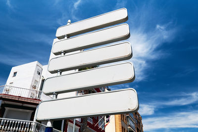 Low angle view of blank information sign against building and sky