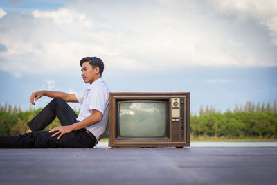 Side view of senior man sitting against sky