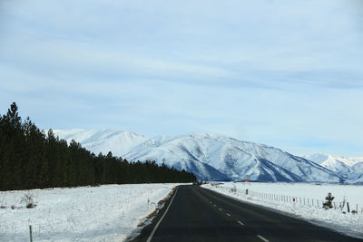 Road amidst snowcapped mountains against sky