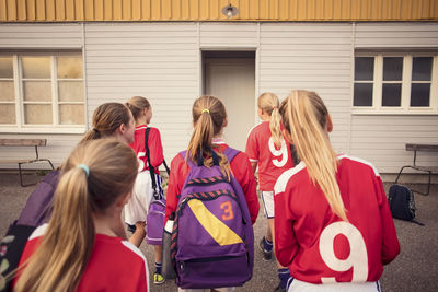 Rear view of female soccer players walking on footpath