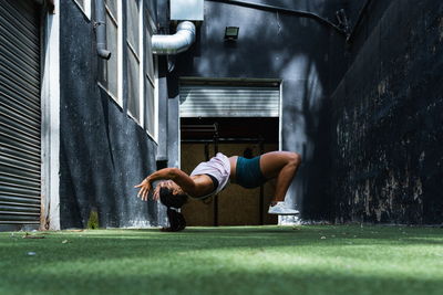 Side view full body of hispanic female athlete in sportswear practicing somersault during active workout